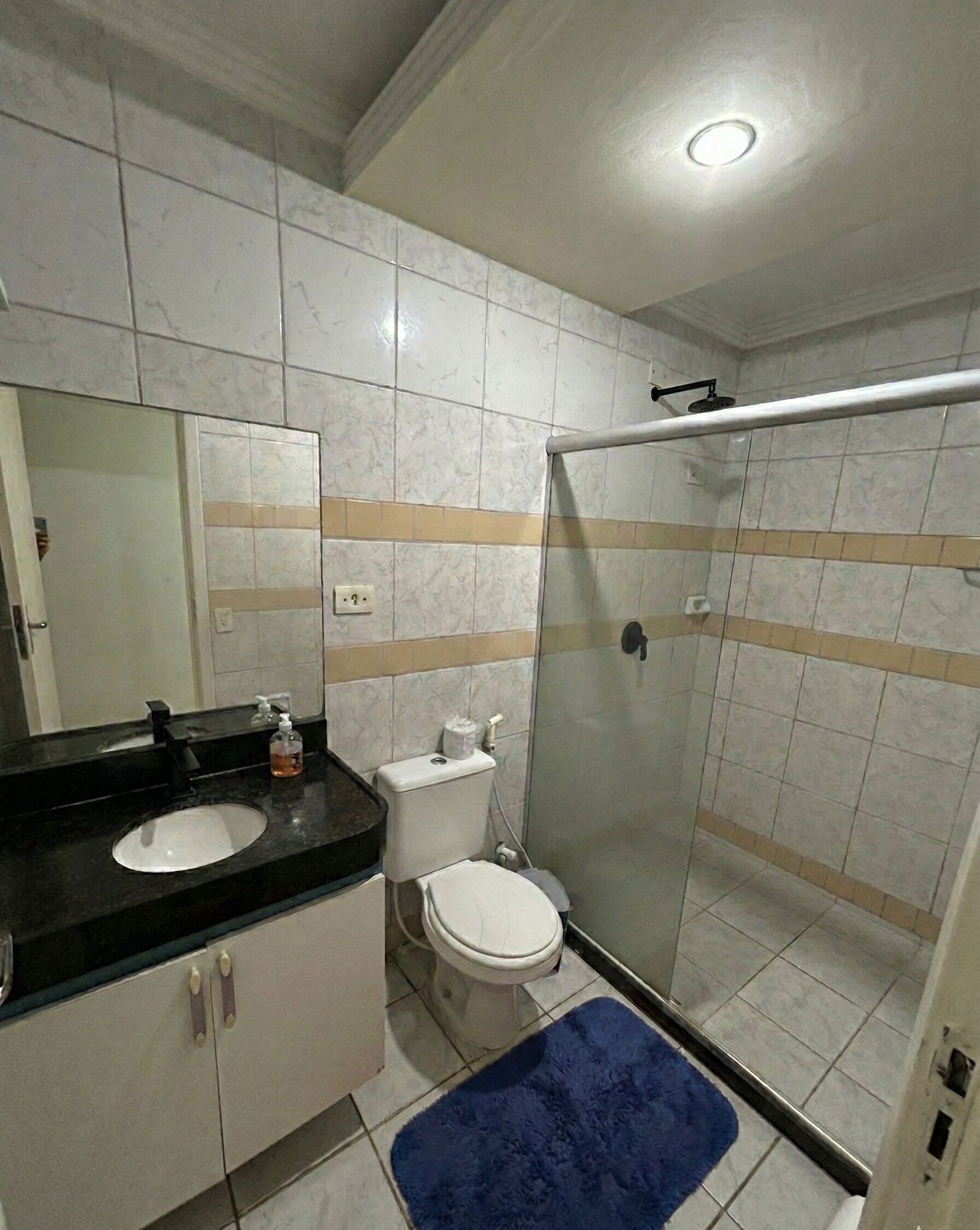 A bathroom with a double sink, toilet, and glass-enclosed shower.