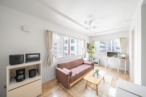A modern living room with a sofa, coffee table, and a TV on a desk. - COURT VILLA SAPPORO 401 (Sapporo)