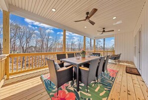 A covered outdoor area with a wooden deck, a table with chairs, and ceiling fans. - Lake Twin Cove - New! (Moneta)