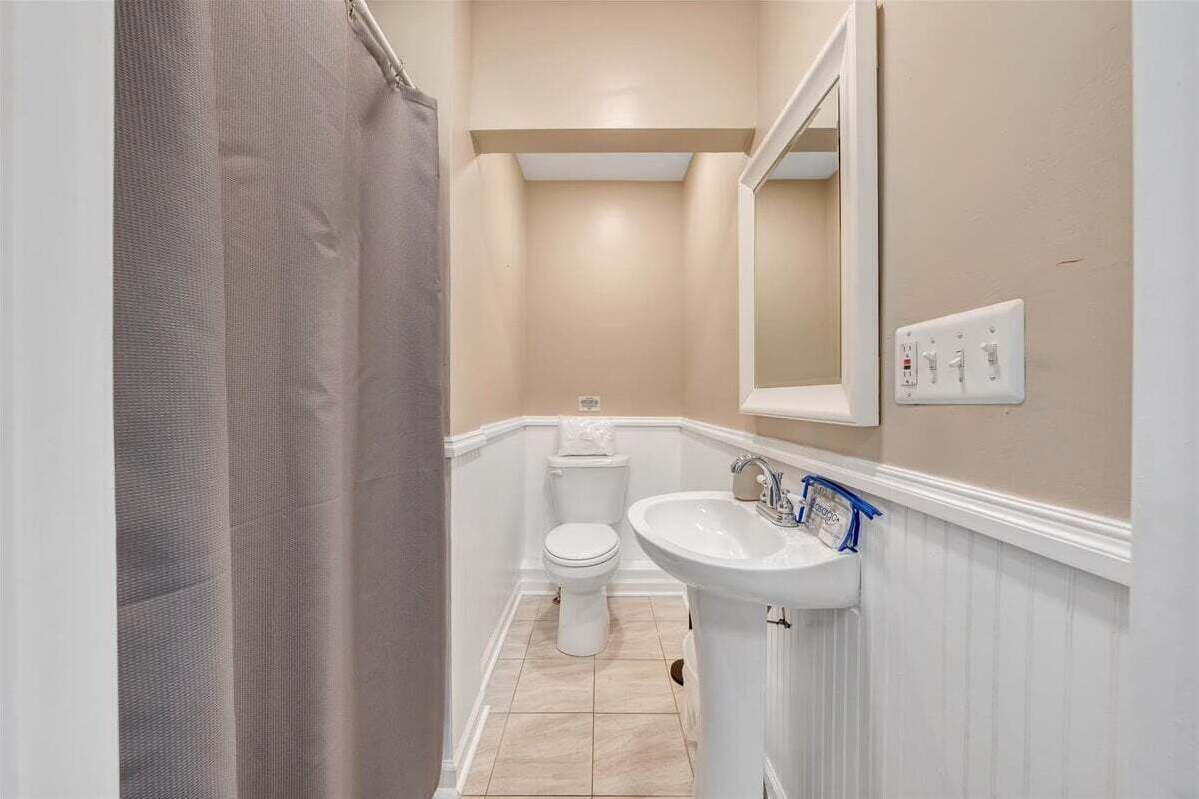 A bathroom with a toilet, sink, and shower curtain.