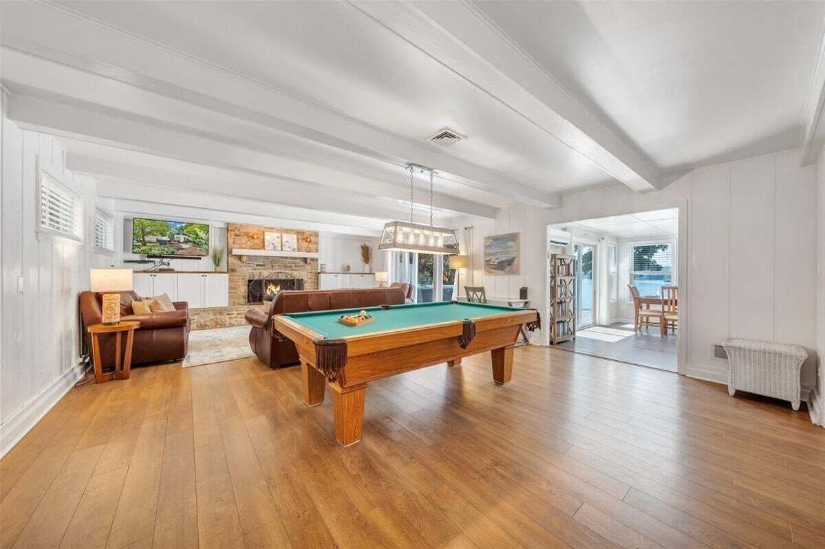 A spacious living room with a pool table, a fireplace, and a view of the outdoors.