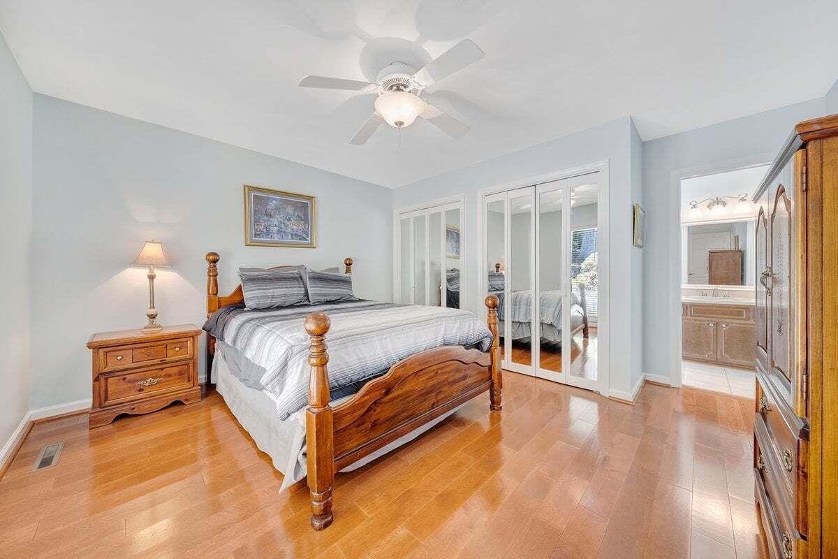 A bedroom with a wooden bed, a nightstand, a ceiling fan, and a wardrobe.