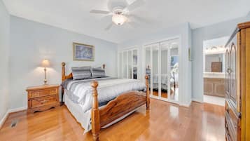 A bedroom with a wooden bed, a nightstand, a ceiling fan, and a wardrobe.