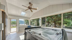 A hot tub on a wooden deck with large windows and a ceiling fan. - Lake Allure - Private Dock, Indoor Pool, and Hot Tub (Huddleston)