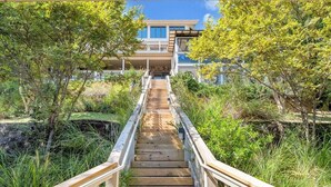 A wooden staircase leading to a house with a balcony, surrounded by greenery. - Lake Allure - Private Dock, Indoor Pool, and Hot Tub (Huddleston)