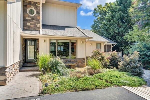 A two-story house with a stone facade, a covered porch, and a landscaped garden. - Lake Allure - Private Dock, Indoor Pool, and Hot Tub (Huddleston)