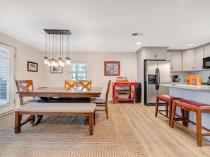 A modern kitchen with a built-in refrigerator, a dining area with a wooden table and chairs, and a red storage cart. - Lake Reflections - Lakefront With Private Dock, & Fire pit (Huddleston)