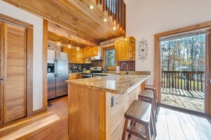 Una cocina moderna con armarios de madera, encimera de granito y una isla grande con taburetes de bar.