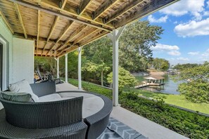 A covered outdoor seating area with wicker furniture, a view of a lake, and a dock. - Kelly Kove - Beach Area Sleeps 14, Private Dock, Pet Friendly (Penhook)