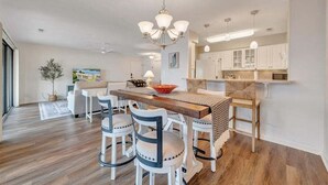 Une cuisine moderne avec des armoires blanches, un îlot central en bois et un lustre.