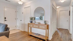 Un couloir avec une console en bois, un miroir et une porte dotée de volets à persiennes.