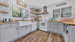 A modern kitchen with white cabinets, wooden countertops, and a copper range hood. - Lakeside Sunsets - Private Dock, Hot Tub & Firepit (Moneta)
