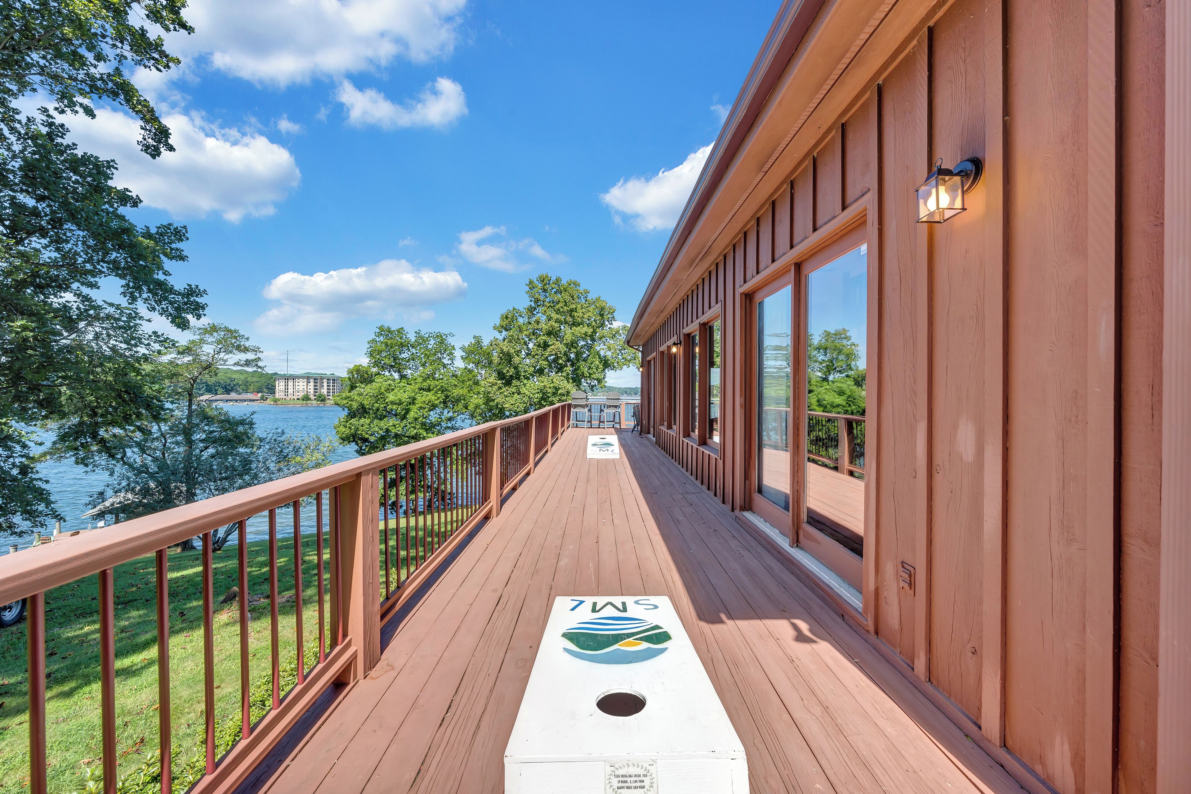 A wooden deck with a railing, a logo, and a view of a lake.