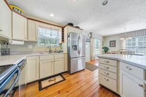 Una cocina con armarios blancos, electrodomésticos de acero inoxidable y piso de madera.