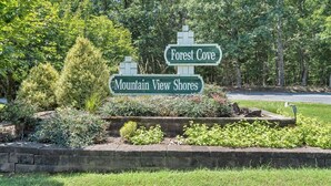 Ein Wegweiser mit der Aufschrift 'Forest Cove' und 'Mountain View Shores', umgeben von Grün.