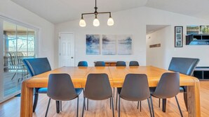 Un espace repas avec une table en bois et des chaises noires, un lustre et des œuvres d’art abstraites accrochées au mur.
