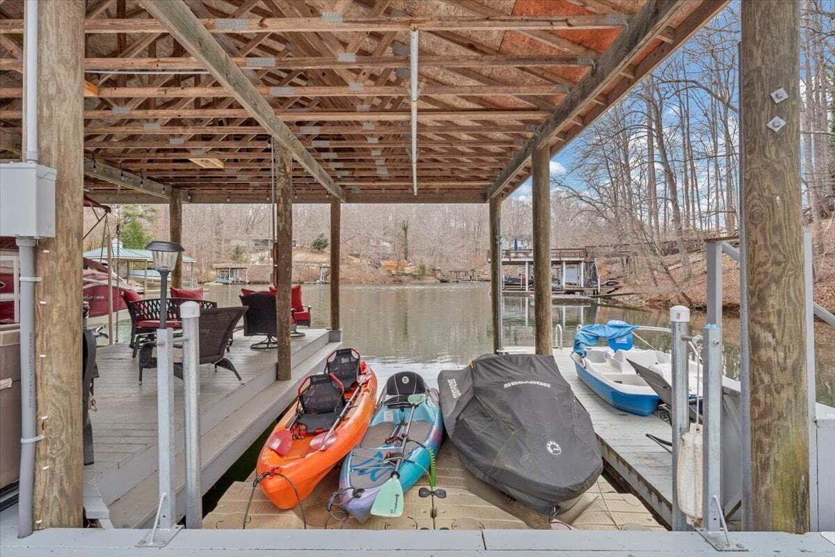 Une zone abritée avec des quais, des kayaks et un bateau, une terrasse en bois et des sièges extérieurs.