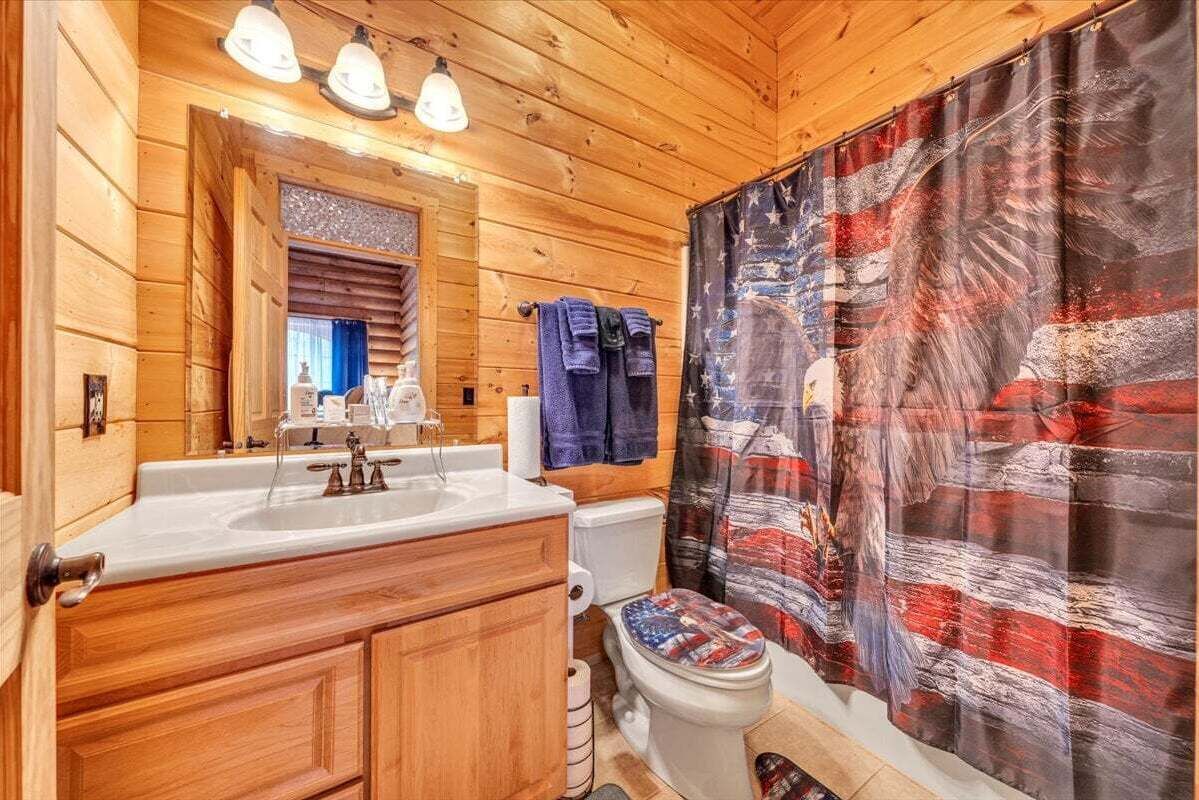 Ein Badezimmer einer Holzhütte mit Waschbecken, Spiegel und Toilette.