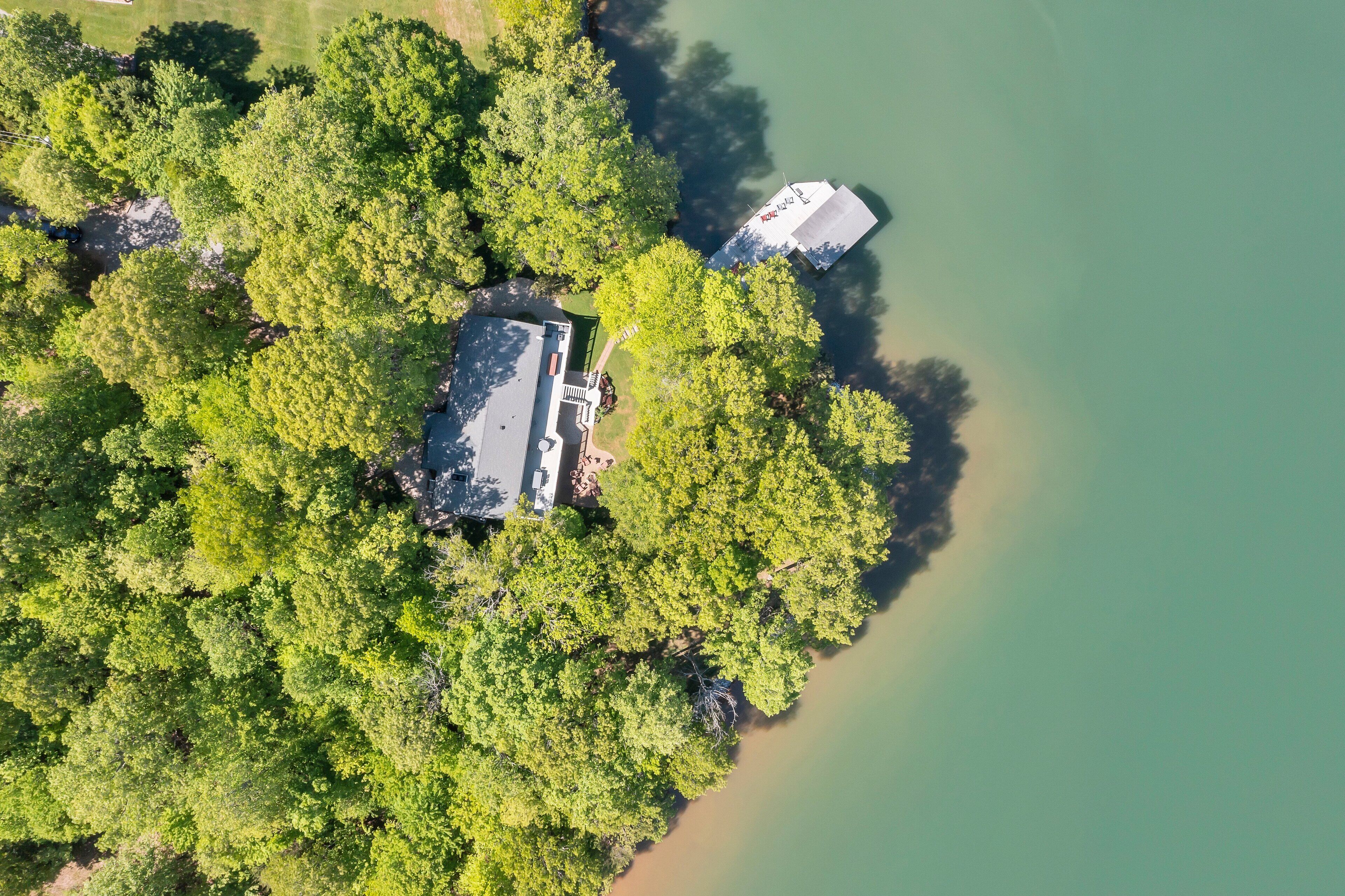 Vista aérea de una propiedad con un edificio grande rodeado de árboles frondosos y una masa de agua.