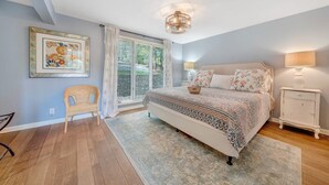 A bedroom with a large bed, a wicker chair, a nightstand, and a ceiling light. - Lake Pleasant - Lakefront, Private Dock, Game Room (Huddleston)