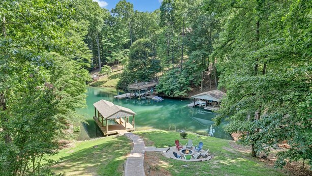 A lakeside lodge with a dock, a small pavilion, and a fire pit area surrounded by lush greenery. - Lake Pleasant - Lakefront, Private Dock, Game Room (Huddleston)