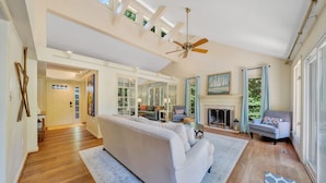 A spacious living room with a high ceiling, a fireplace, and a large window. - Lake Pleasant - Lakefront, Private Dock, Game Room (Huddleston)