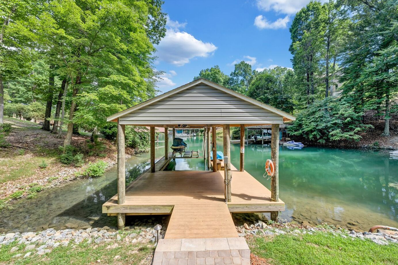 A wooden dock extending into a calm river, surrounded by lush greenery.