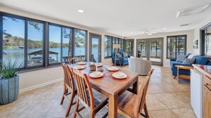 A spacious dining area with a large table set for six, overlooking a lake. - Lake Harmony - Lakefront Home w/ Private Dock, & Fire Pit (Huddleston)