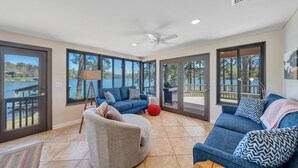 A spacious living area with a large window, a ceiling fan, and a view of a deck and water. - Lake Harmony - Lakefront Home w/ Private Dock, & Fire Pit (Huddleston)