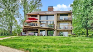A multi-story building with a covered outdoor seating area and a grassy lawn. - Dancing Water - Sleeps 10, Private Dock, Game Room & Hot Tub (Moneta)