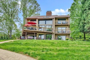 A multi-story building with a covered outdoor seating area and a grassy lawn. - Dancing Water - Sleeps 10, Private Dock, Game Room & Hot Tub (Moneta)