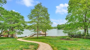 A paved pathway leading to a lakeside area with picnic tables and a dock. - Dancing Water - Sleeps 10, Private Dock, Game Room & Hot Tub (Moneta)