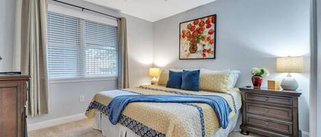 A bedroom with a bed, bedside lamps, a ceiling fan, and a window with blinds.