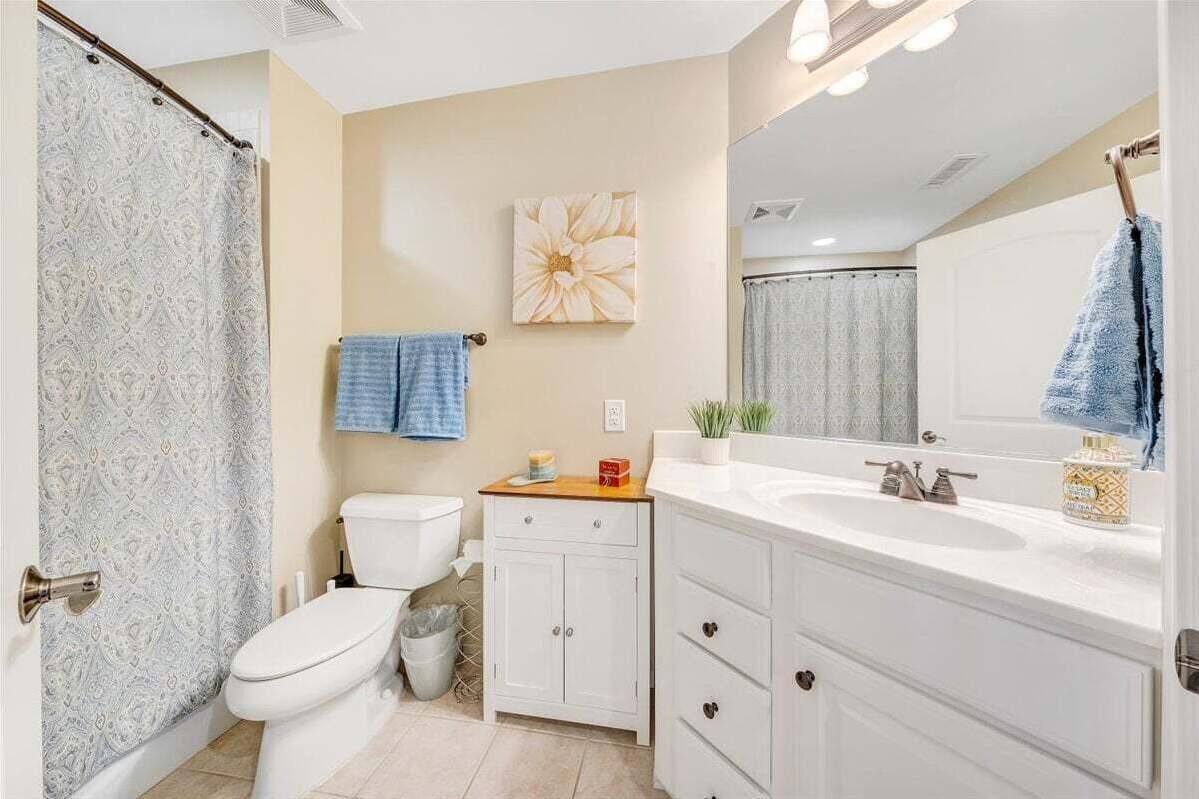 A bathroom with a toilet, a sink, a mirror, and a shower curtain.