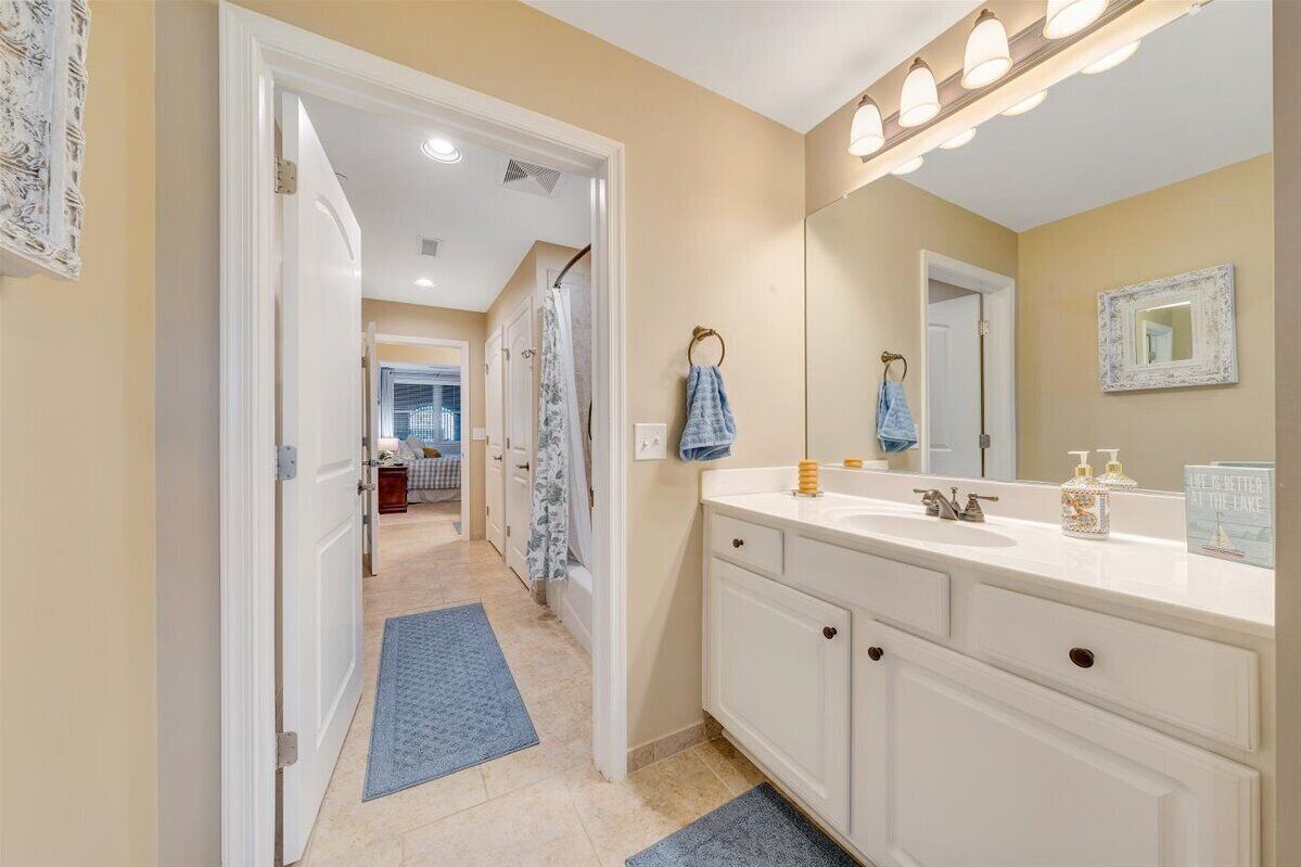 A bathroom with a white vanity, a large mirror, and a towel rack.