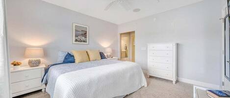 A bedroom with a bed, nightstands, a dresser, and a ceiling fan.