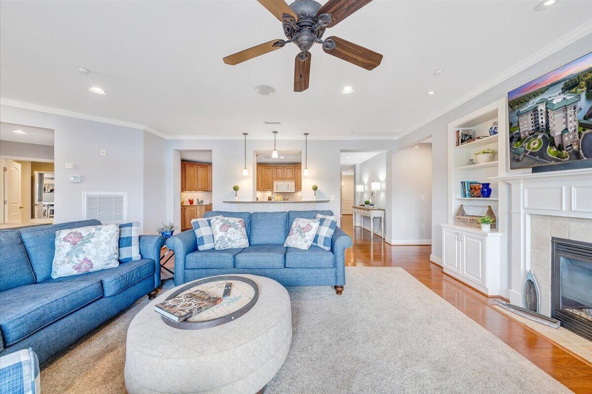 A spacious living room with a blue sofa, a round coffee table, and a fireplace.