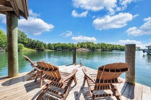 A wooden dock with two Adirondack chairs facing a lake, surrounded by trees and a clear sky. - Sunrise Retreat - Sleeps 12, Lakefront Home With Hot Tub (Huddleston)