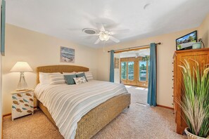 A bedroom with a bed, a nightstand, a ceiling fan, a window with curtains, and a view of the outdoors. - Stargaze - Lakefront With Private Dock (Huddleston)