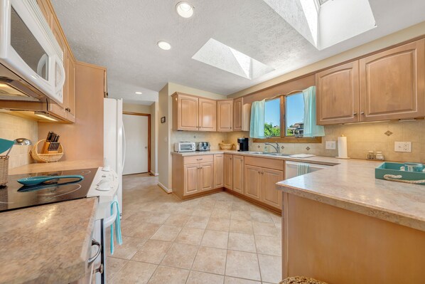 A modern kitchen with wooden cabinets, a built-in oven, and a skylight. - Stargaze - Lakefront With Private Dock (Huddleston)