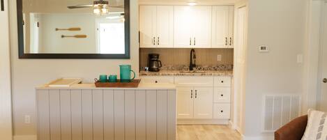 Una cocina moderna con gabinetes blancos, una isla central y un ventilador de techo.