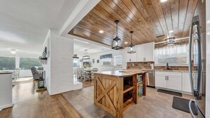 A modern kitchen with a wooden ceiling, white cabinetry, and a central island. - Paradise Point - Lakefront Home With Private Dock! (Goodview)