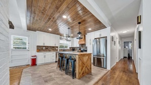 A modern kitchen with a central island, wooden ceiling, and white cabinetry. - Paradise Point - Lakefront Home With Private Dock! (Goodview)