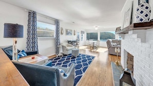 A modern living room with a fireplace, a dining area, and a view of the outdoors. - Paradise Point - Lakefront Home With Private Dock! (Goodview)