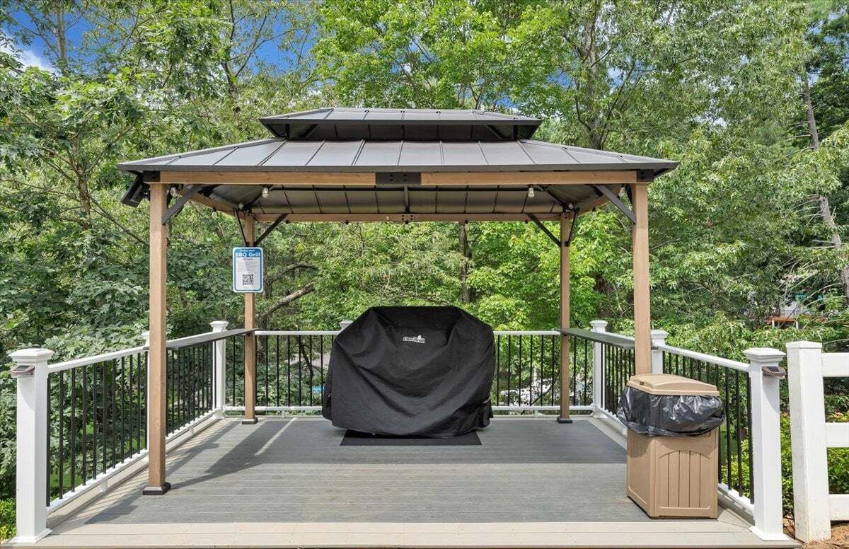 A covered outdoor area with a pergola, a barbecue grill, and a trash bin.