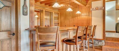 A wooden interior with a bar area, wooden chairs, and a sign that reads "My Bar Official Rules".