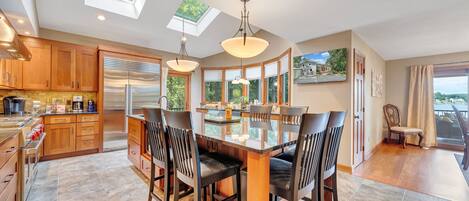 A modern kitchen with a central island, wooden cabinets, and a large window.