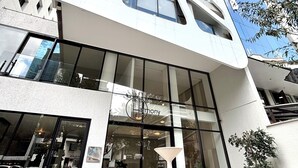 A modern building with a unique architectural design, featuring large windows and a glass entrance. - Luxury Studio in Harmony - Best Area Quito, Pool, Gym & Fast WiFi (Quito)
