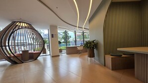 A modern reception area with a curved ceiling, a seating area with a unique spherical design, and a reception desk. - Luxury Studio in Harmony - Best Area Quito, Pool, Gym & Fast WiFi (Quito)