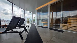A modern interior with large windows, a long bench, and a view of the cityscape. - Luxury Studio in Harmony - Best Area Quito, Pool, Gym & Fast WiFi (Quito)